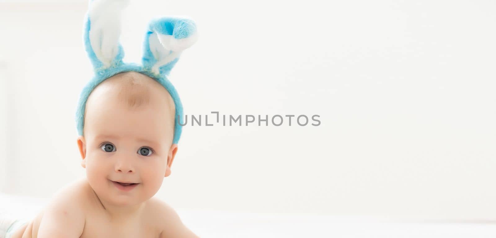 happy caucasian baby girl six months old wearing bunny ears headband by Andelov13