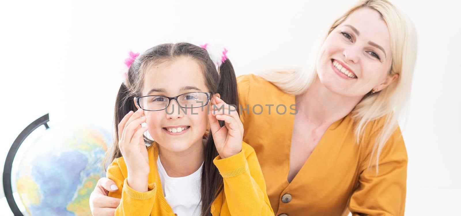 Private lesson. Attentive young woman tutor teacher help little girl pupil with studying math language correct mistakes explain learning material. Smiling mother assist small daughter with home task by Andelov13