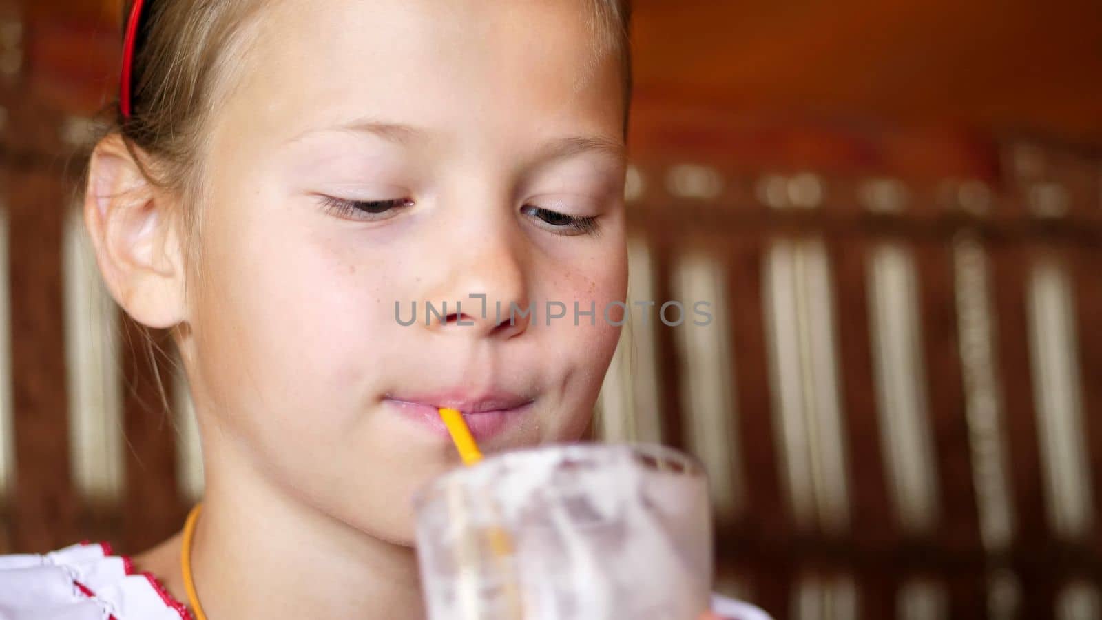 happy smiling teen girl child drinks a milkshake in cafe. she is dressed in Ukrainian national clothes, embroidery, vishivanka. High quality photo