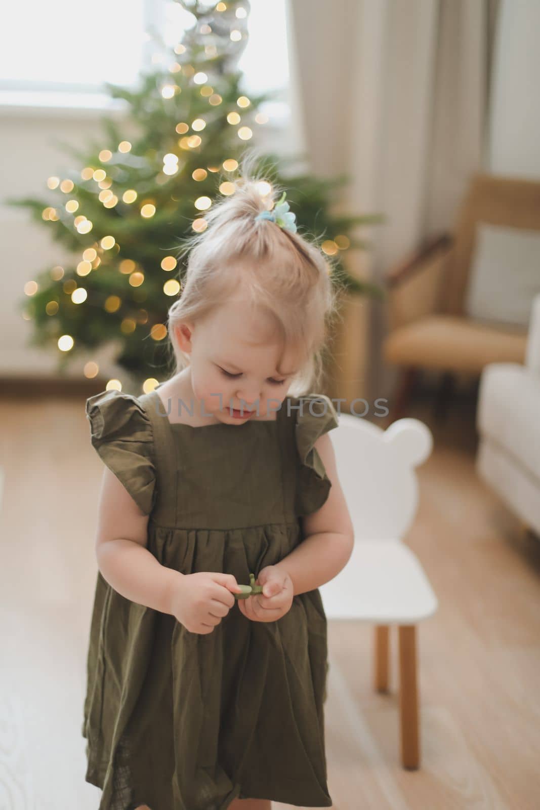 Cute little child girl and the Christmas tree indoors. Merry Christmas and Happy Holidays