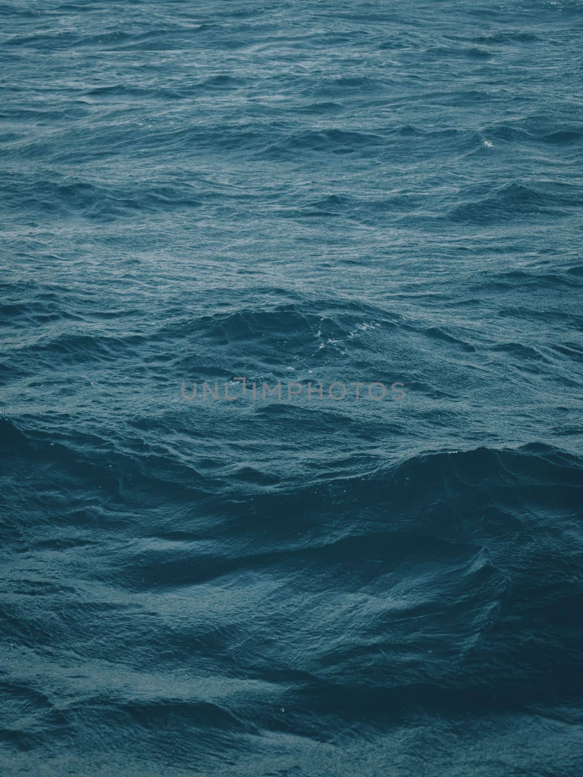 Dark blue-green color of water surface with waves in middle of endless deep sea. Endless wavy expanse of blue sea water. Dark blue waves in deep ocean. Raging aquamarine waves on surface of the water