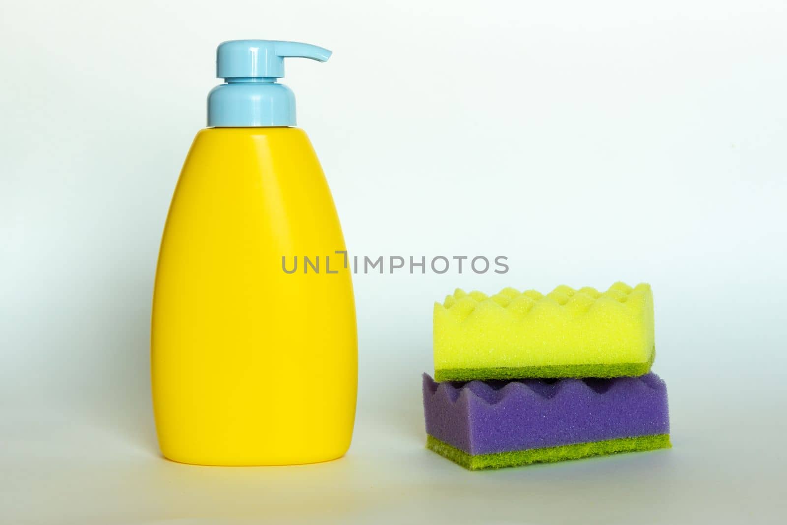 Stack of multi-colored dish wash sponges with bottle of soap. Household cleaning scrub pad. Home cleaning concept. by Ri6ka