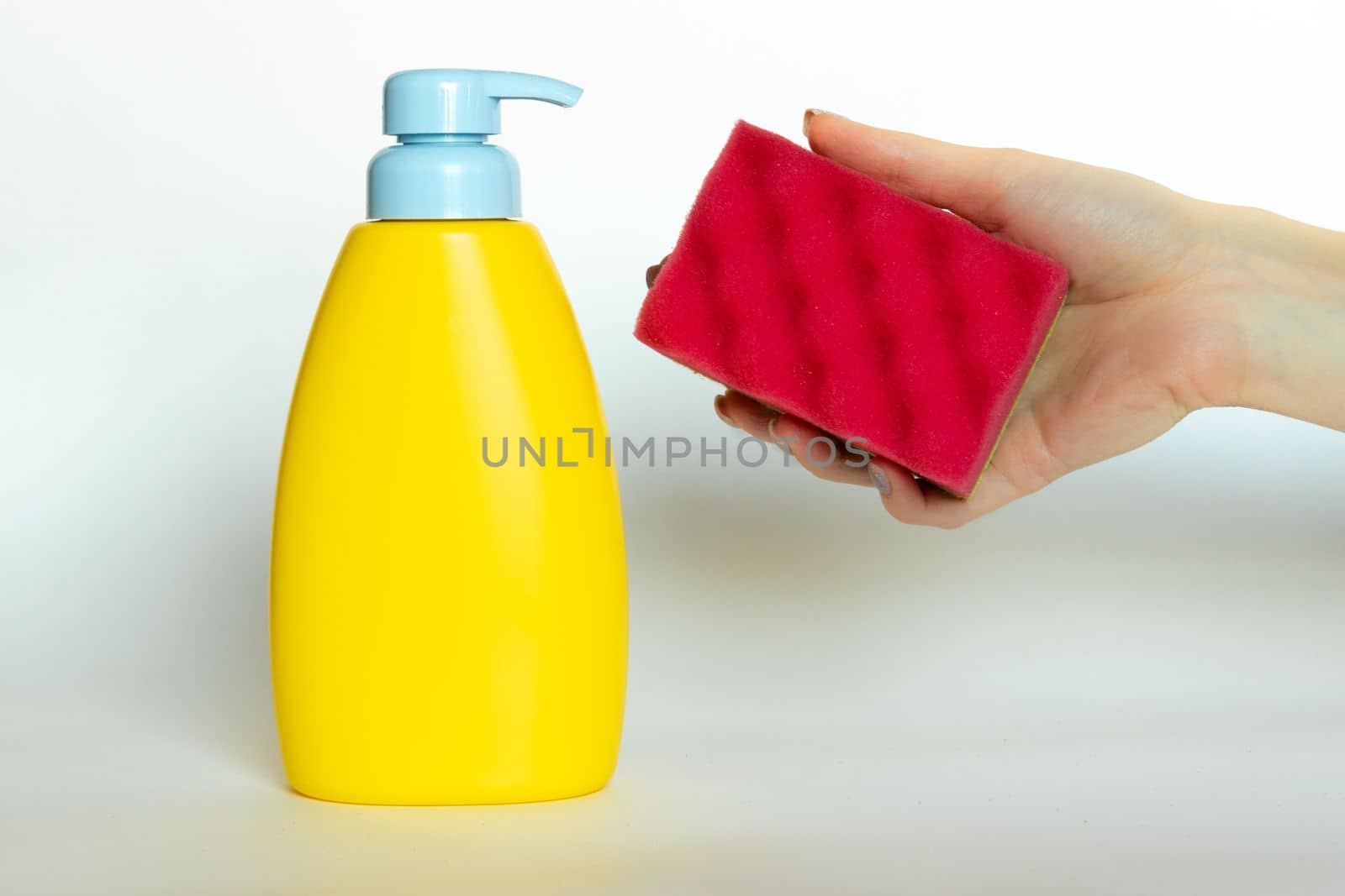Stack of multi-colored dish wash sponges with bottle of soap. Household cleaning scrub pad. Home cleaning concept.