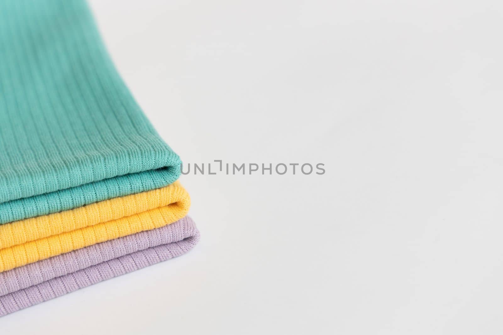 Stack folded purple, yellow, green baby cotton clothing on white background isolation. Copy space. For advertising, commercial,mock up. by Ri6ka