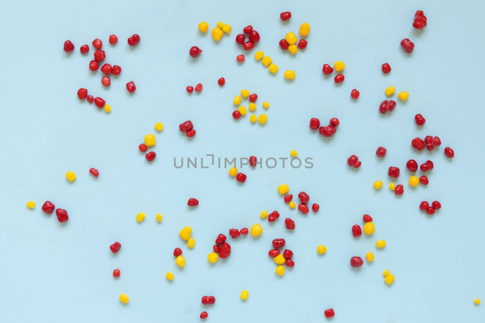 Red and yellow colored candy nerds sprinkled on a blue background