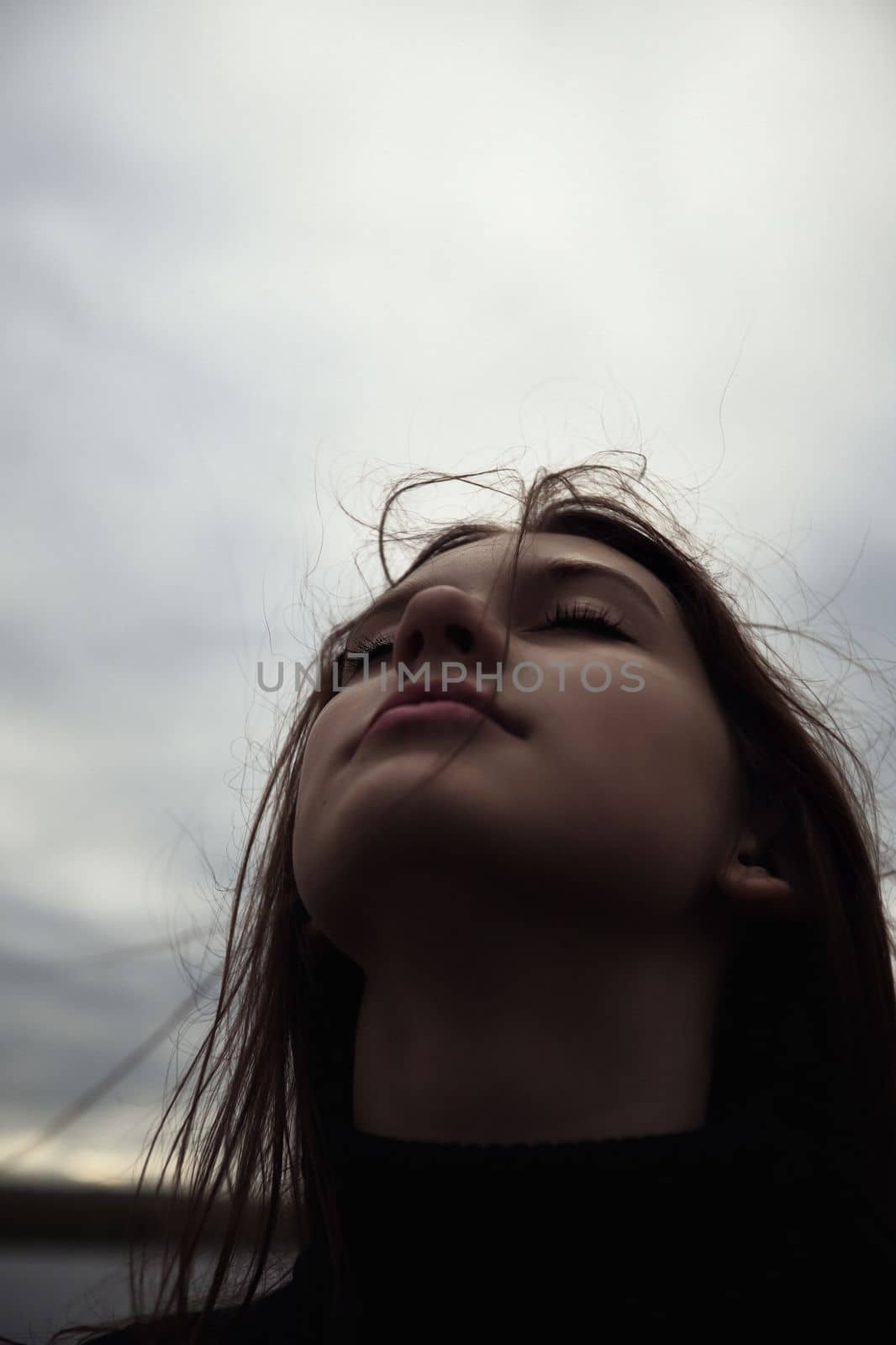 cute teenager girl closing her eyes breathes fresh air the wind inflates luggage. High quality photo