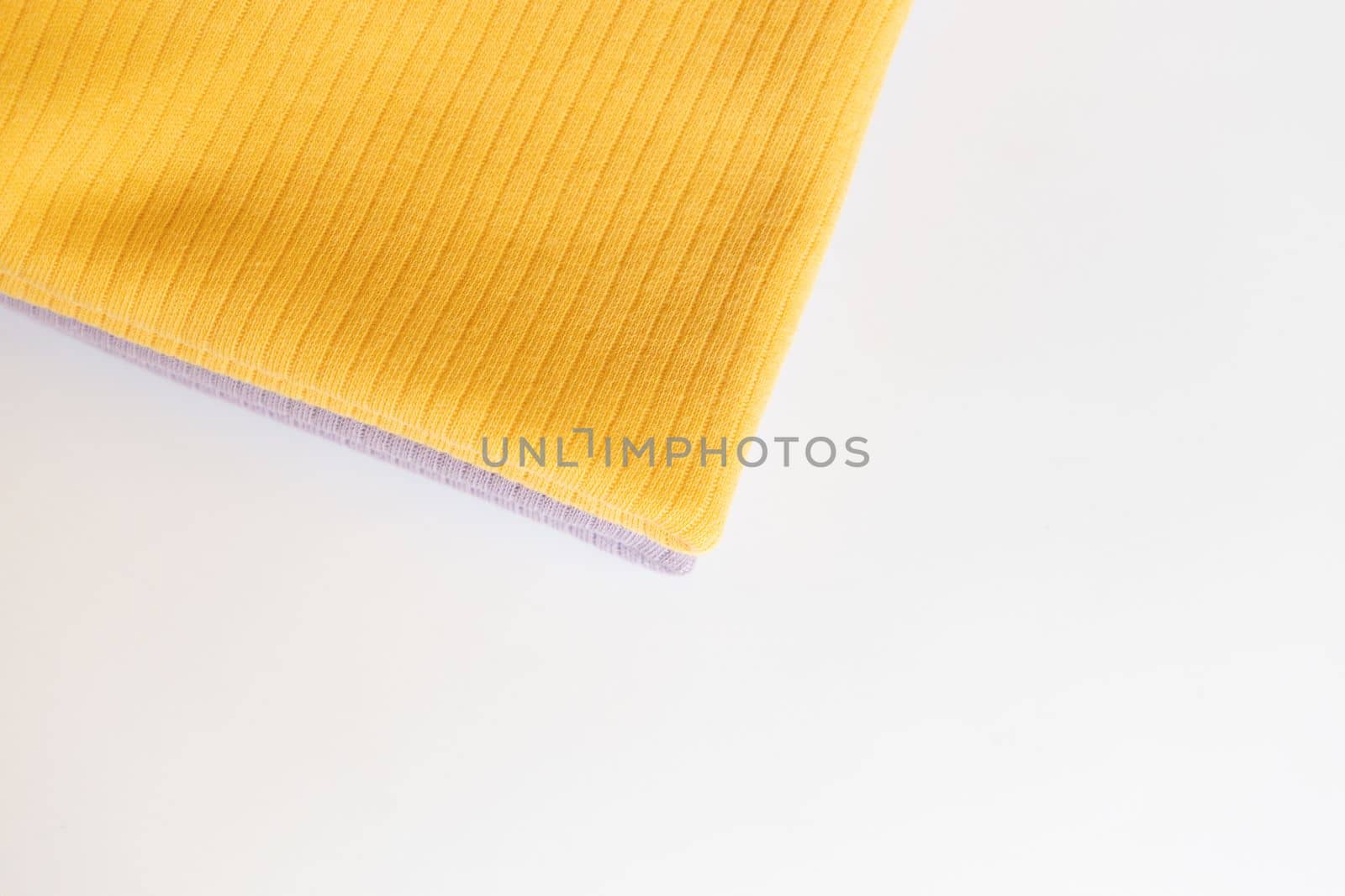 Stack folded purple, yellow baby cotton clothing on white background isolation. Copy space. For advertising, commercial,mock up. by Ri6ka