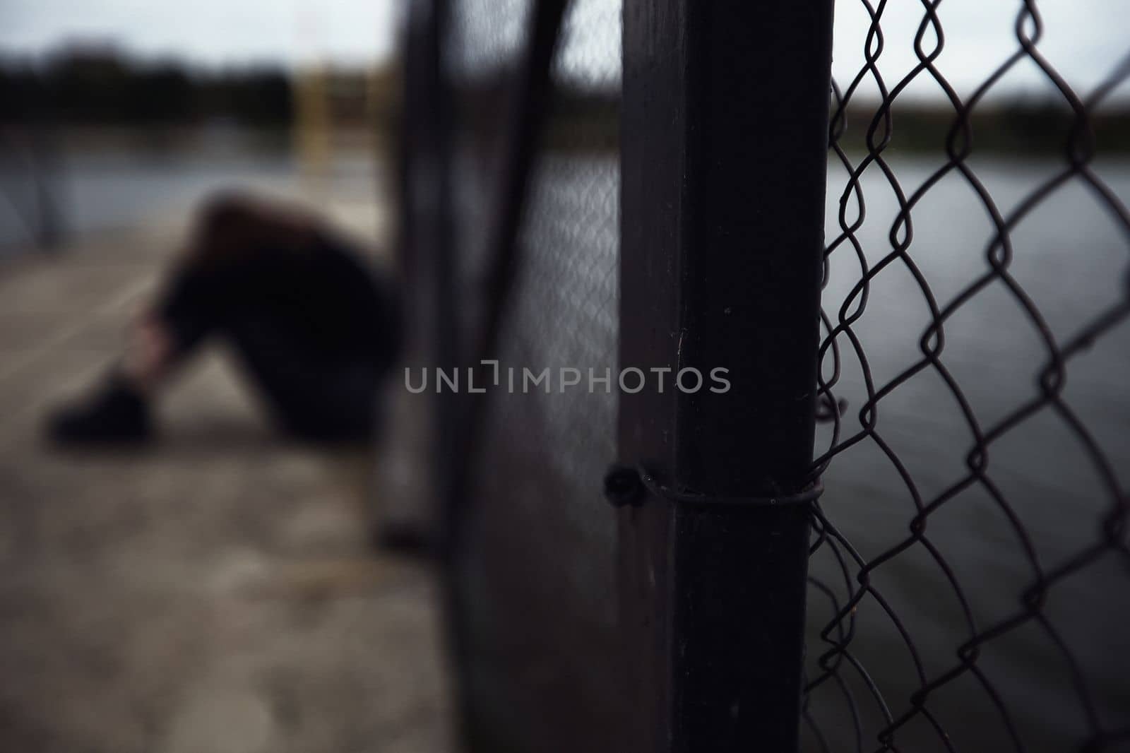 bullying teen girl aloofness young detachment a lonely helpless woman thinks she sits in black clothes about life and does not want to live looks at a gloomy photo into the distance and a renunciate thinks alone with herself and is bored upset on a pier by the water sits on a pier in the evening. High quality photo