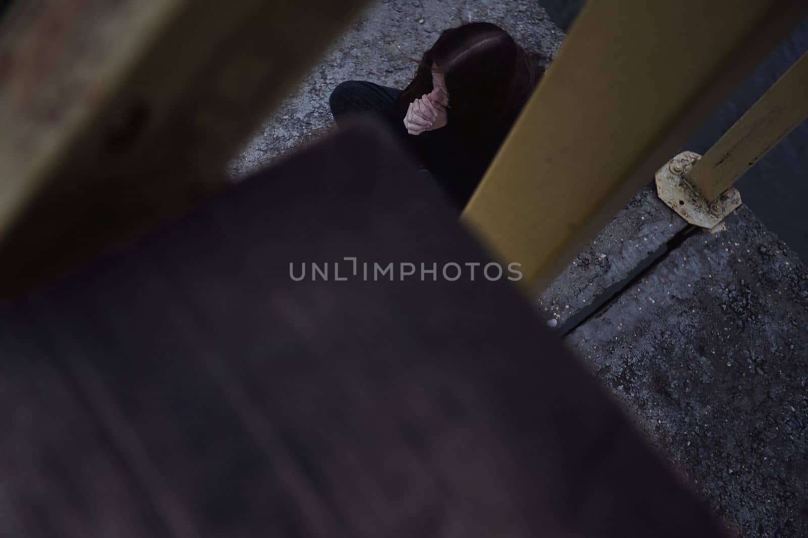 bullying teen girl aloofness young detachment a lonely helpless woman thinks she sits in black clothes about life and does not want to live looks at a gloomy photo into the distance and a renunciate thinks alone with herself and is bored upset on a pier by the water sits on a pier in the evening. High quality photo