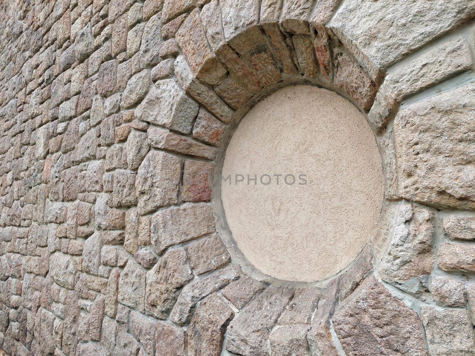 Round blind window in the stone wall of the church. background photo