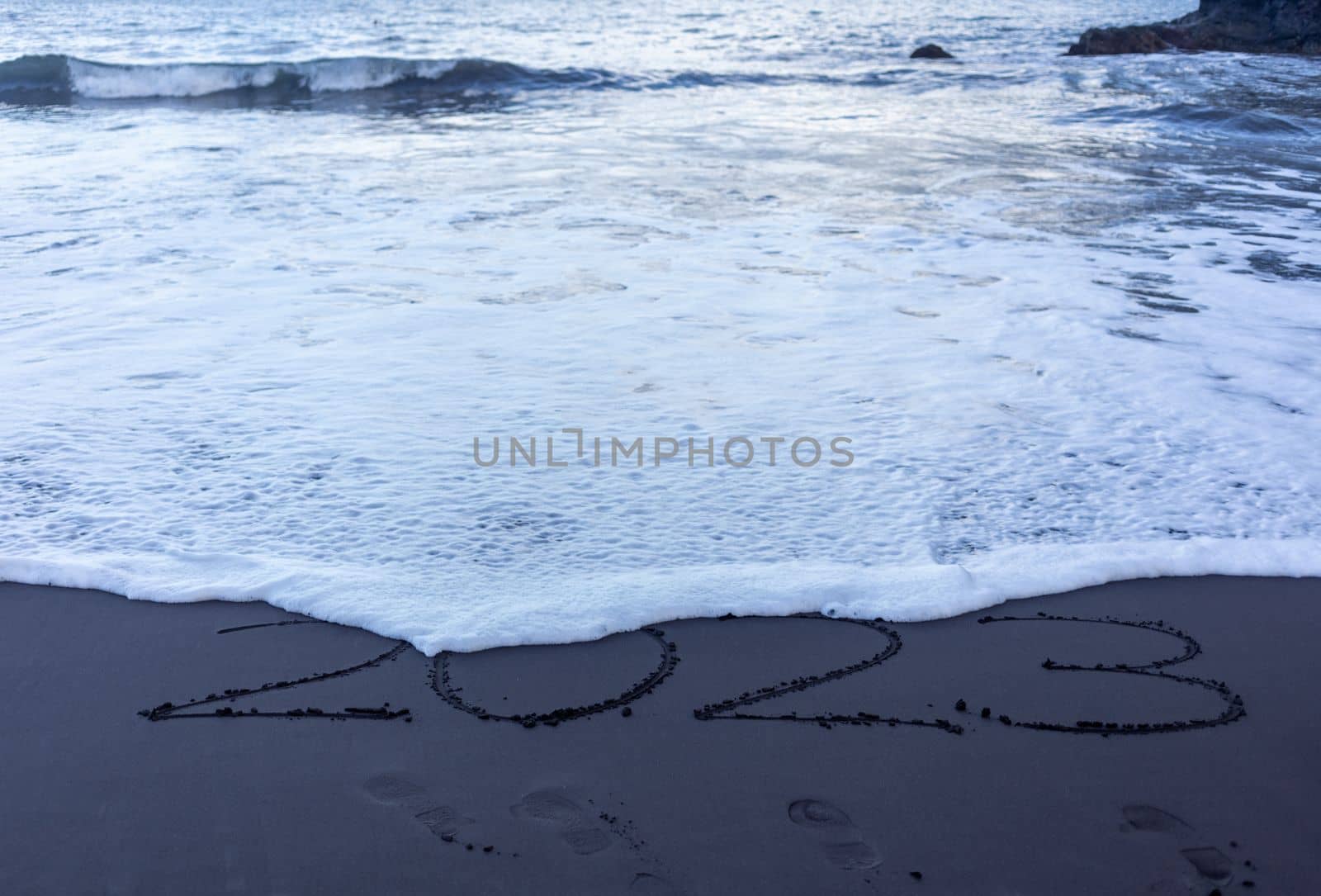 Year 2023 symbol written on black beach sand. High quality photo