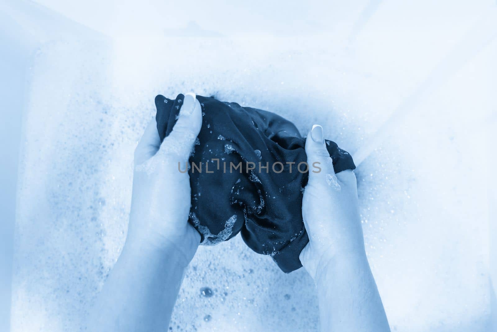 Top view of female hands washing black clothes by Mariakray