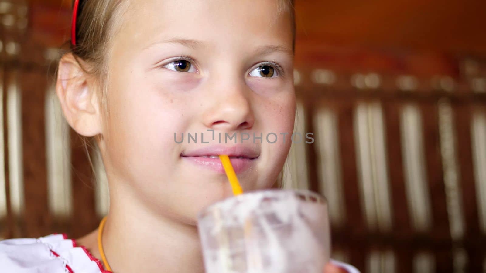 happy smiling teen girl child drinks a milkshake in cafe. she is dressed in Ukrainian national clothes, embroidery, vishivanka. High quality photo