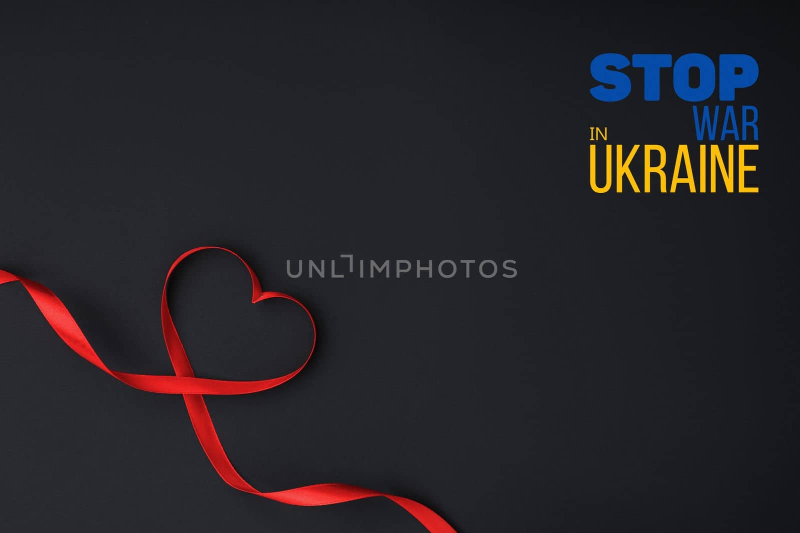 red ribbon laid out in the shape of heart on black background with words stop war in ukraine. concept needs help and support, truth will win