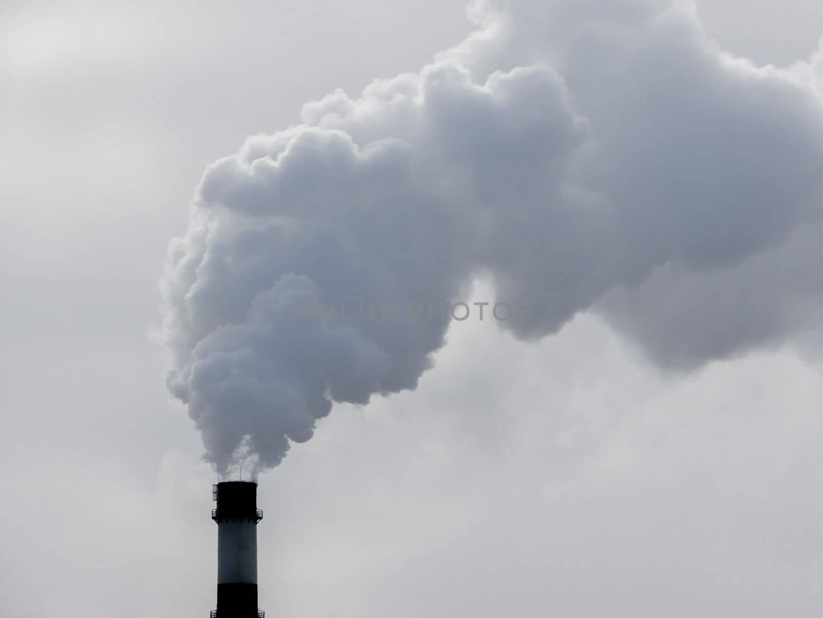 industrial chimneys with heavy smoke causing air pollution on gray sky background. Dyrty smoke