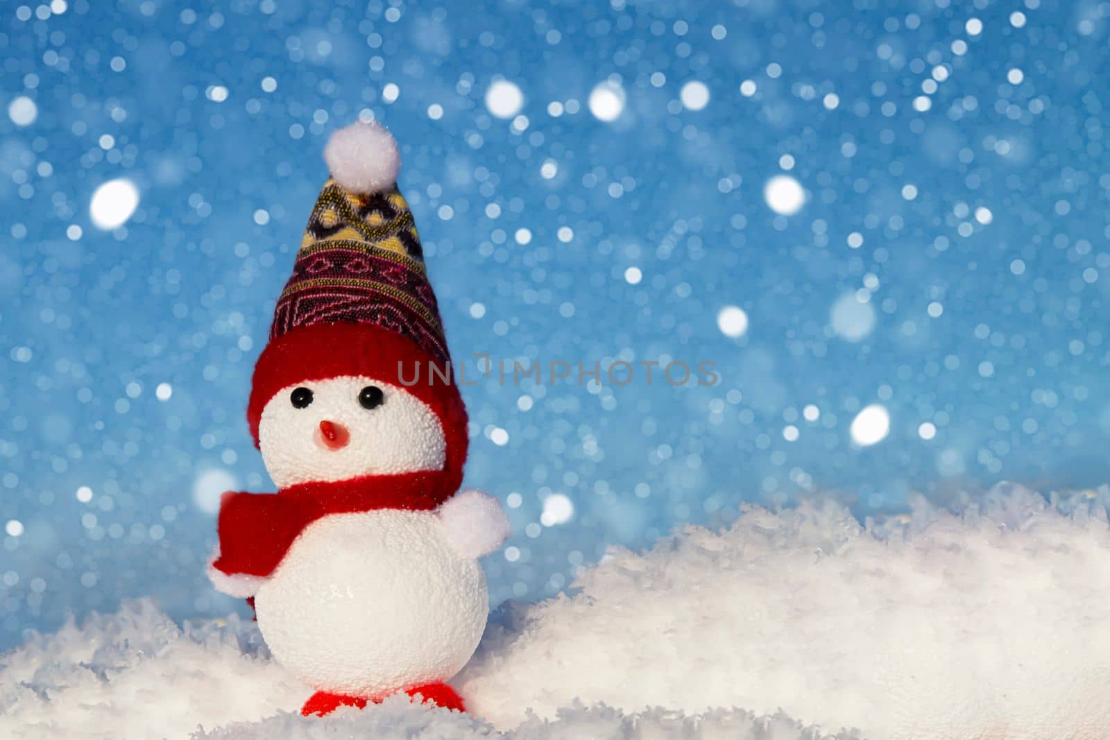 The snowman is standing in the snow and it is snowing. Festive Christmas card. Winter background for the design.