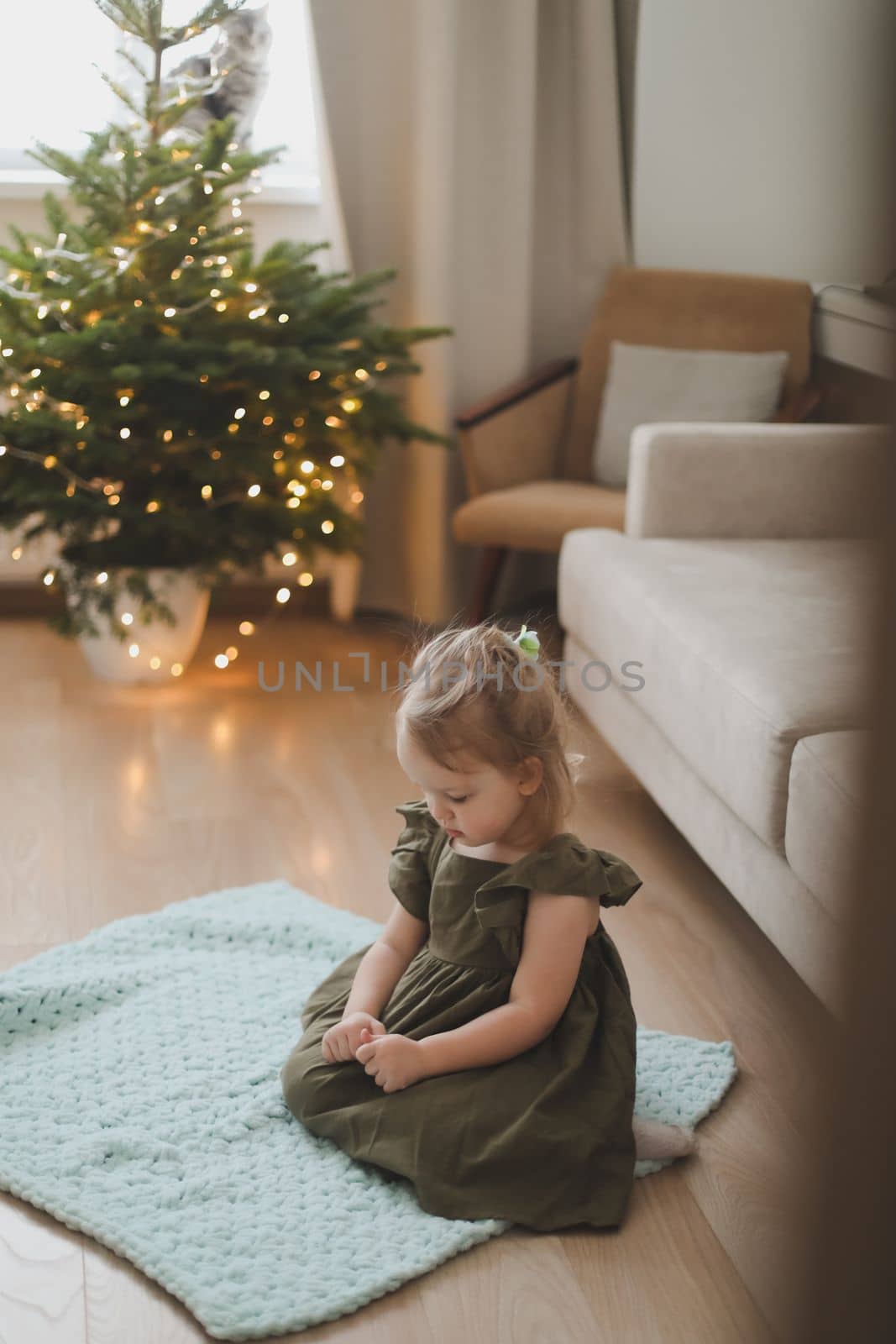 Cute little child girl and the Christmas tree indoors. Merry Christmas and Happy Holidays
