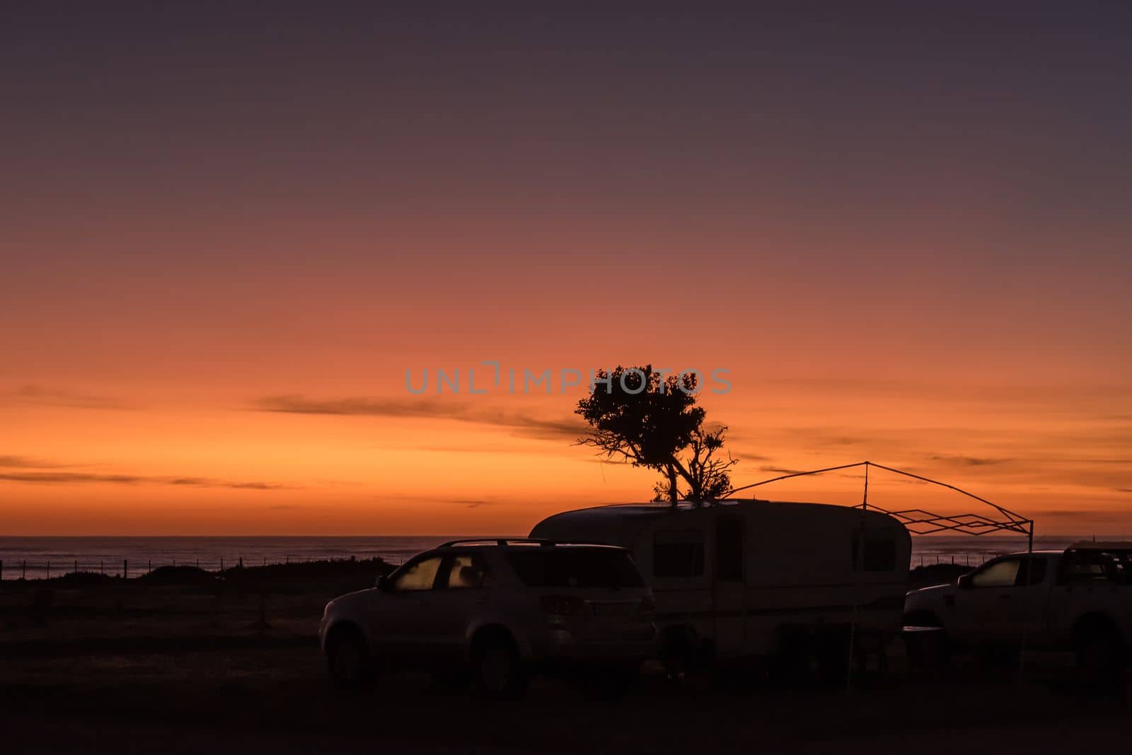Sunrise at the caravan park in Struisbaai, in the Western Cape Province. Vehicles and a caravan is visible