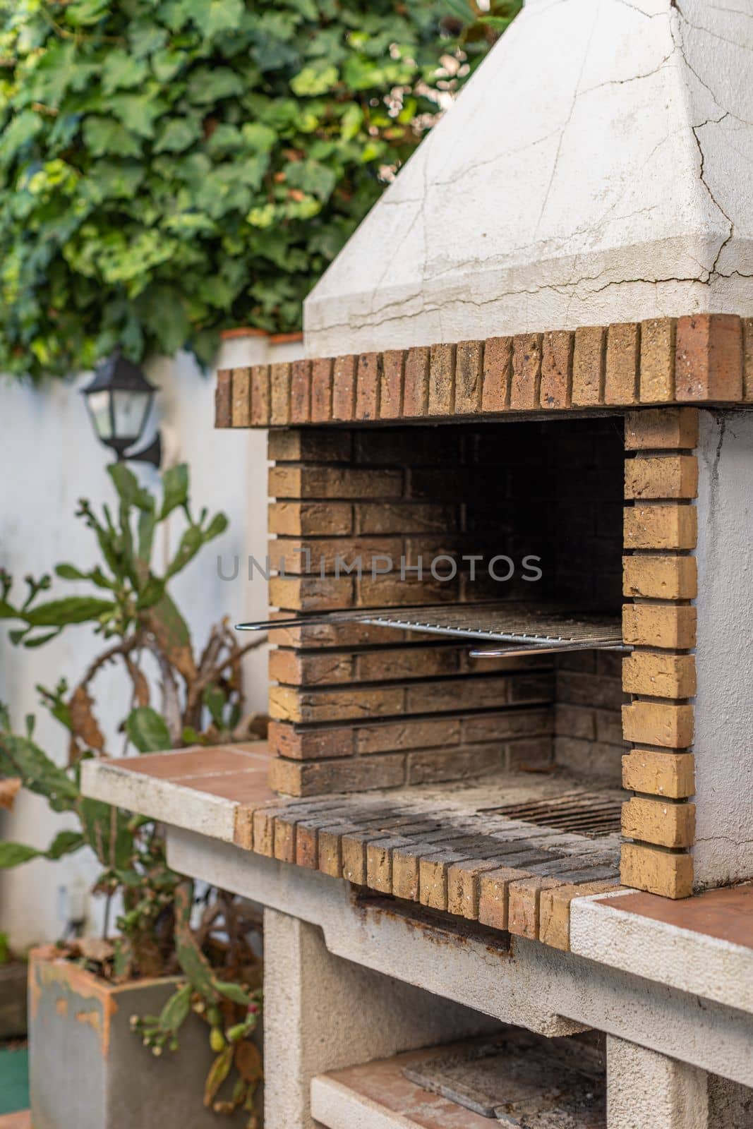 Barbecue grill made of yellow brick and concrete for cooking meat dishes and vegetables outdoors in the courtyard of the house. Cooking food on a brick grill. Picnic in the backyard of my own house. by apavlin