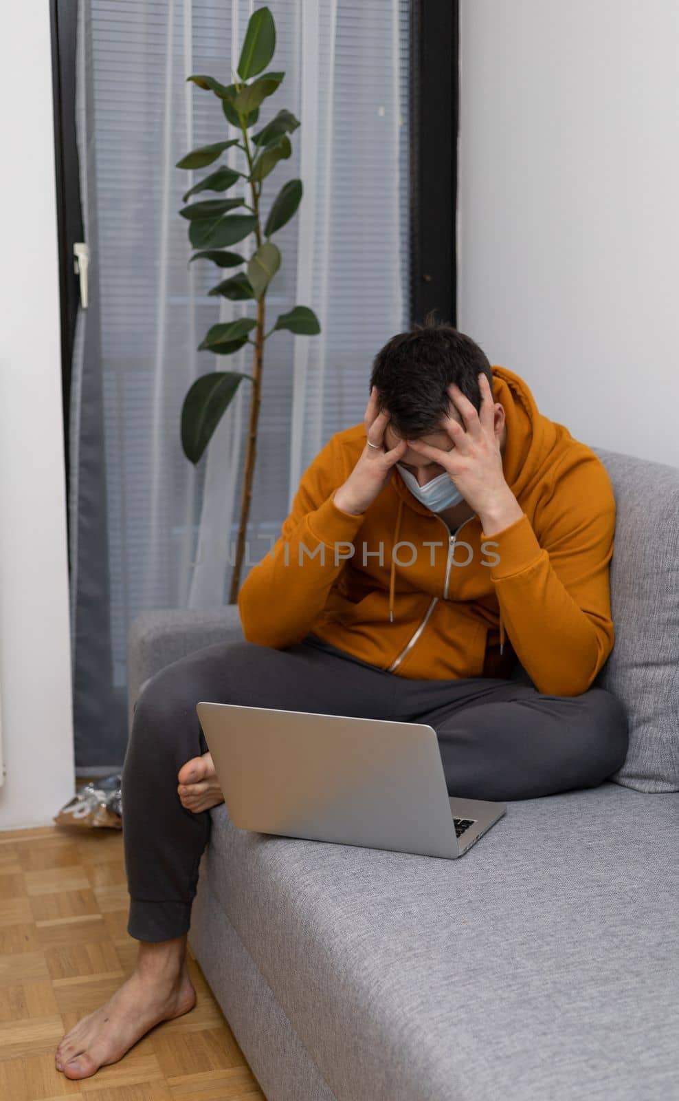 upset young man at home watching at laptop by Chechotkin