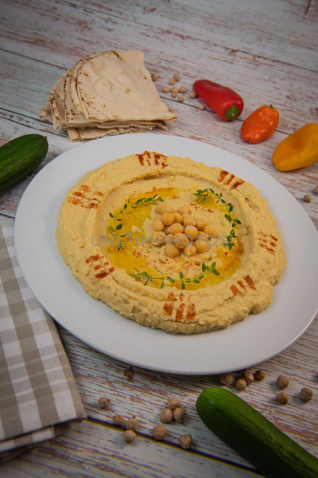 Homemade hummus with tahini plate with olive oil and paprika and pita isolated on brown background. High quality photo