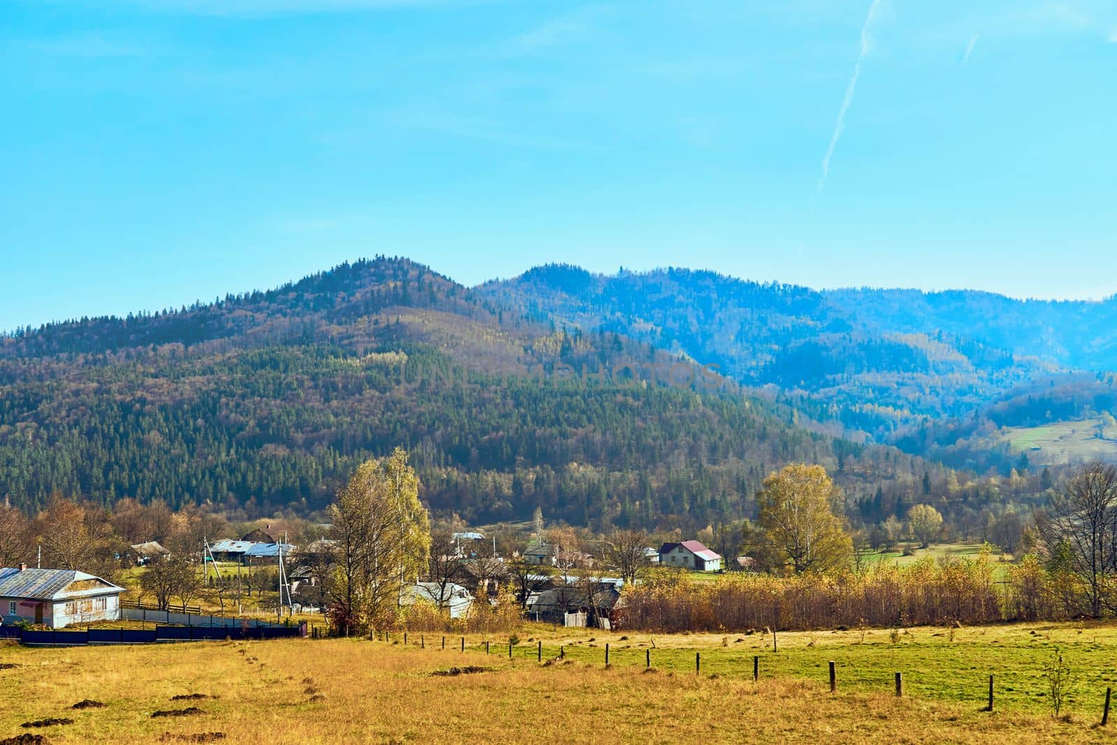 Autumn is one of the four temperate seasons. Outside the tropics, autumn marks the transition from summer to winter. Small village with fields at the foot of the autumn mountains