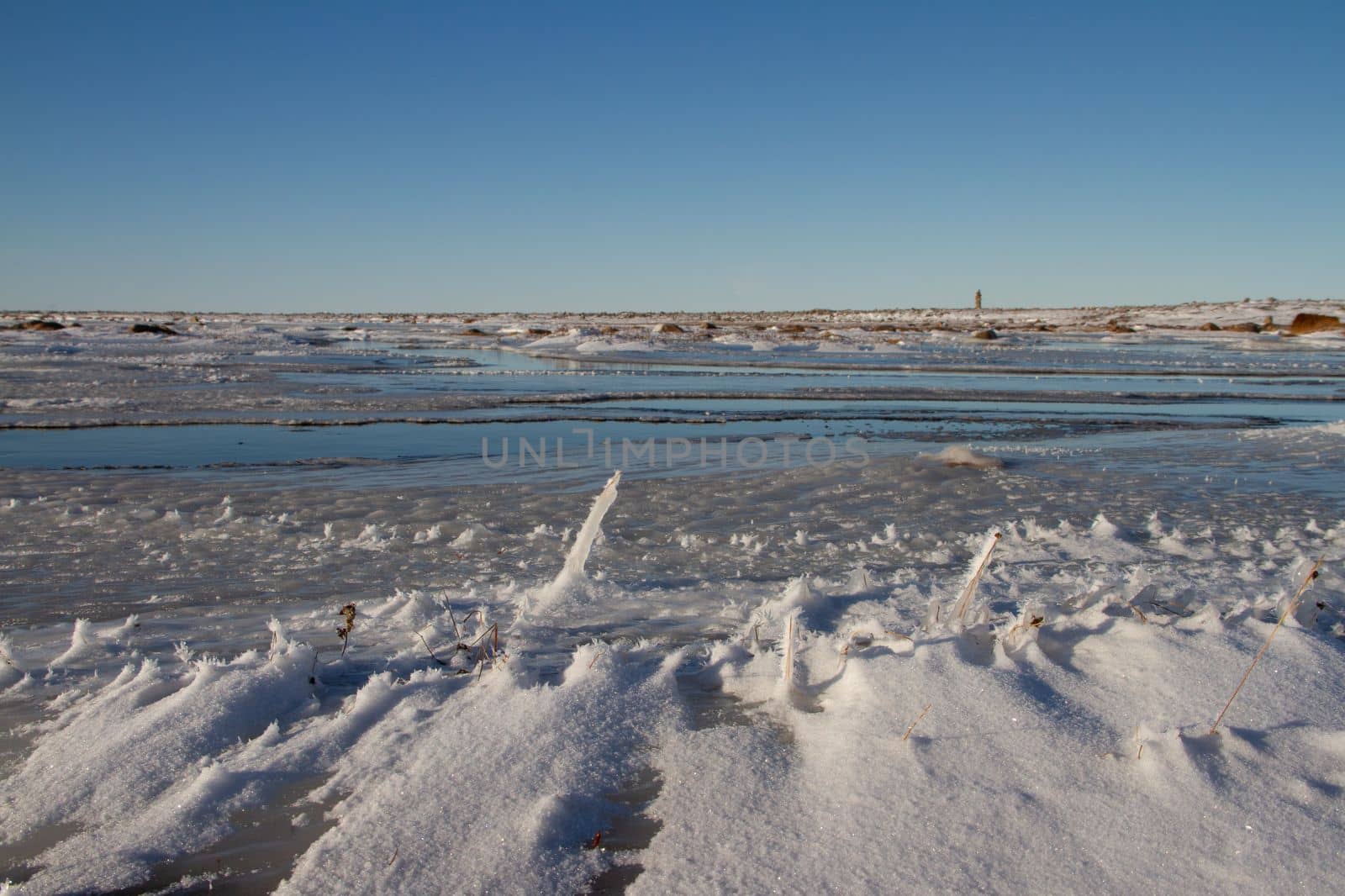 Arctic landscape - frozen arctic tundra in Nunavut over a snow covered waterbody on a clear cold day, near Arviat, Nunavut