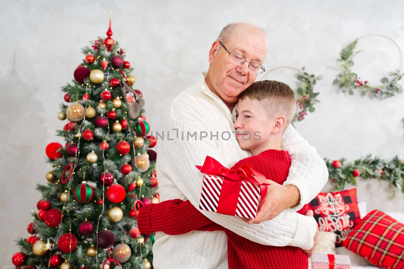Happy Grandson giving grandpa a Christmas present. Cute little boy is giving his father a gift and smiling. Christmas wonder.
