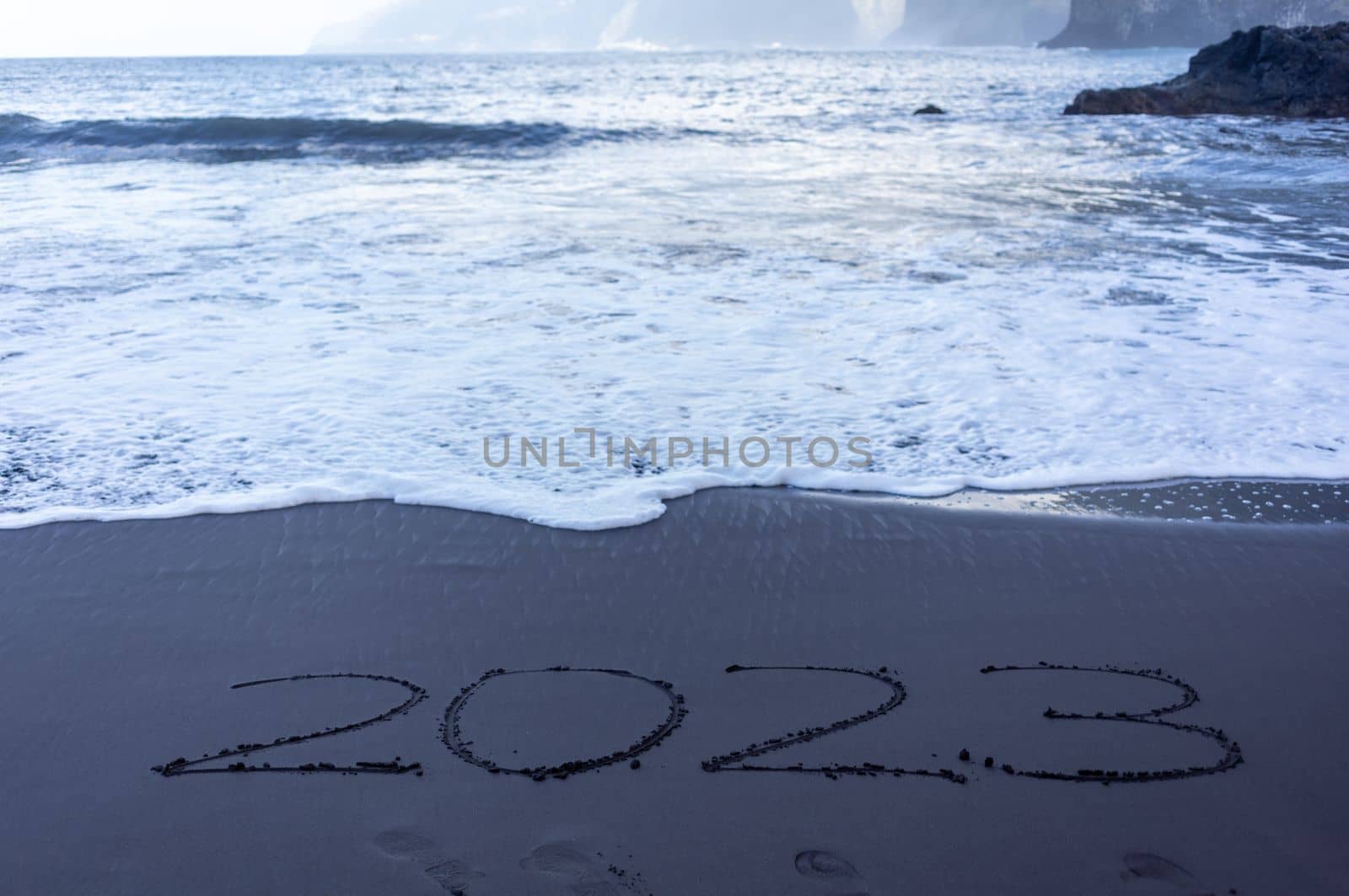 Year 2023 symbol written on black beach sand by Chechotkin