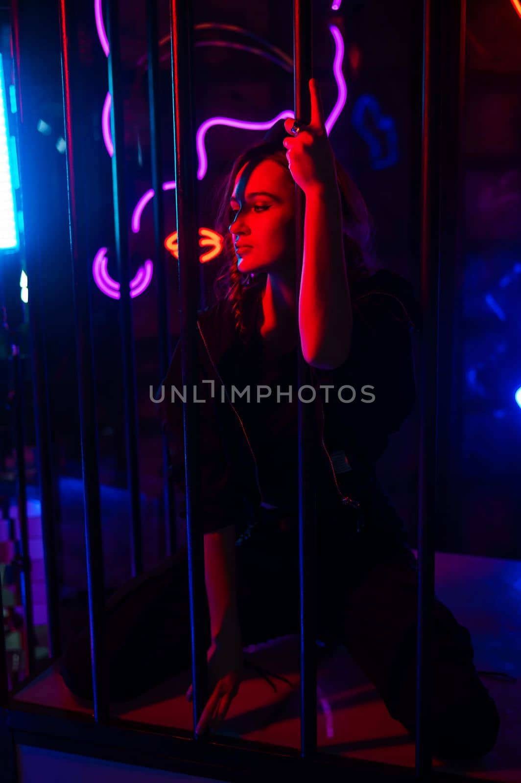 Caucasian woman in a cage in a neon studio