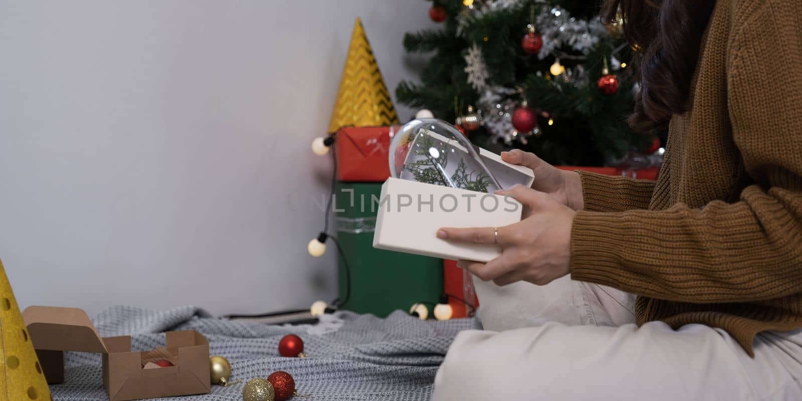 Smiling asian woman in festive mood holding wrapped gift box with brown ribbon in hands, stretching out present to camera, celebrating Merry Christmas