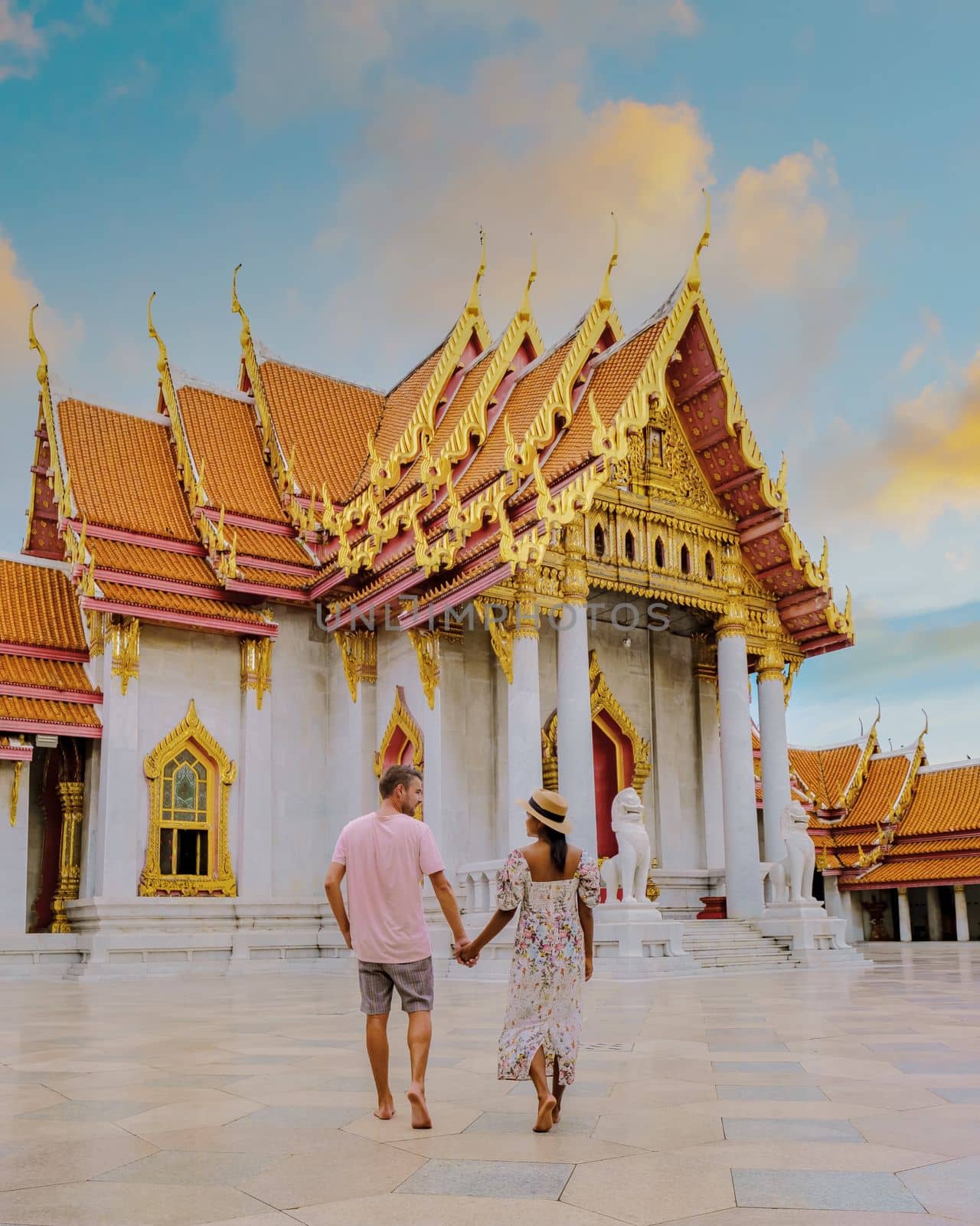 Wat Benchamabophit temple in Bangkok Thailand, The Marble temple in Bangkok. Asian woman with a hat and European men visiting a temple, a couple on a city trip in Bangkok