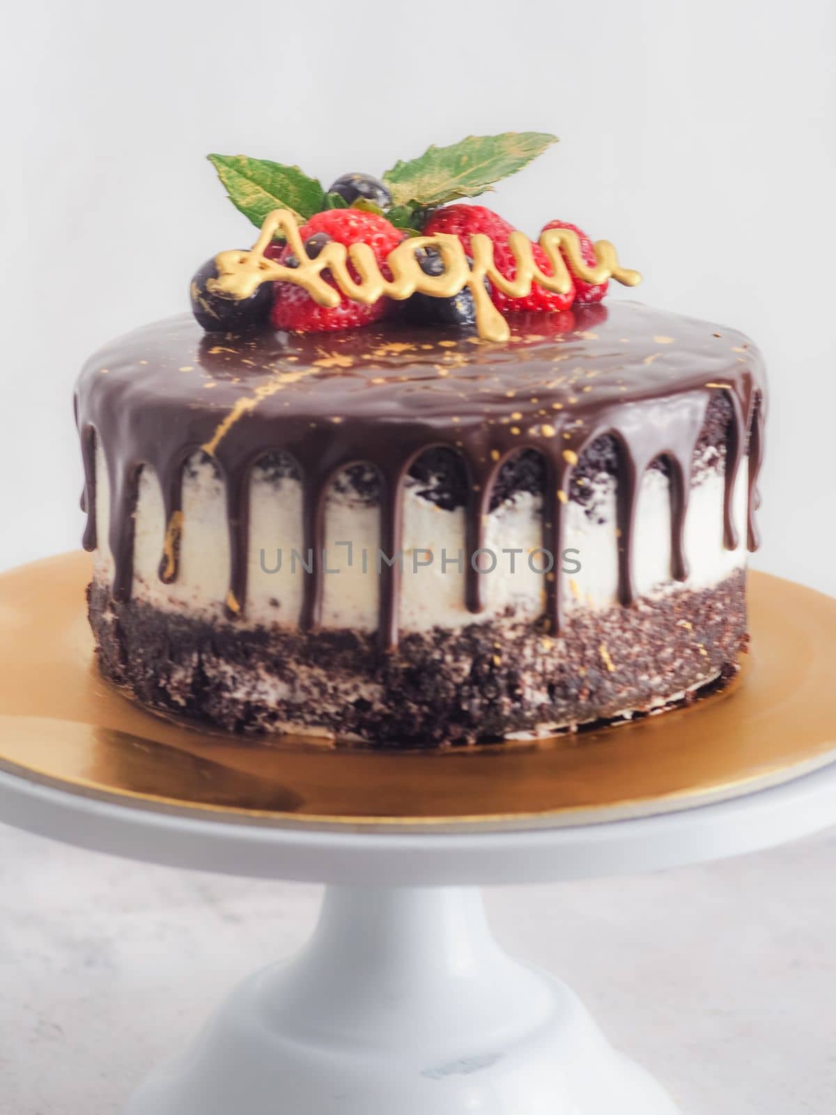 dark chocolate drips birthday sweet cake, fresh fruits Raspberry strawberry blueberry cranberry on top, decorated with golden edible paint