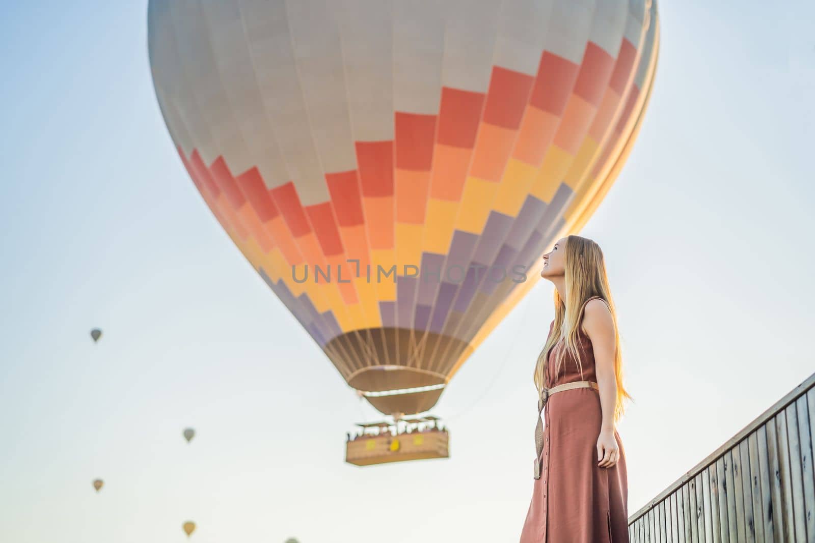 Tourist woman looking at hot air balloons in Cappadocia, Turkey. Happy Travel in Turkey concept. Woman on a mountain top enjoying wonderful view.
