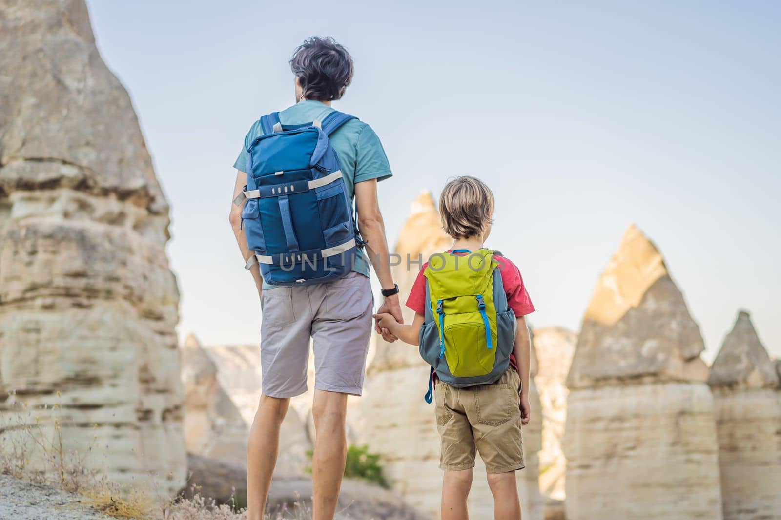 Father and son tourists on background of Unique geological formations in Love Valley in Cappadocia, popular travel destination in Turkey. Traveling with children in Turkey concept.