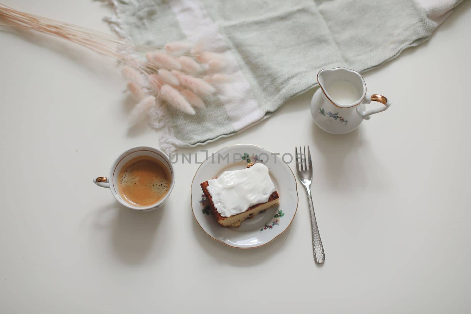 White cup with coffee and milk jug on a white wooden background, closeup. Energy breakfast, morning routine concept. coffee cup and milk pitcher on white table background