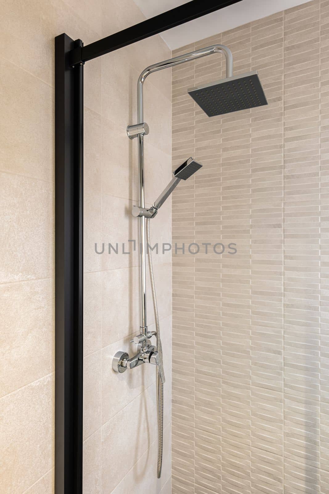 Modern shower zone with black rain head and hand held shower. Beige tiles in the bathroom
