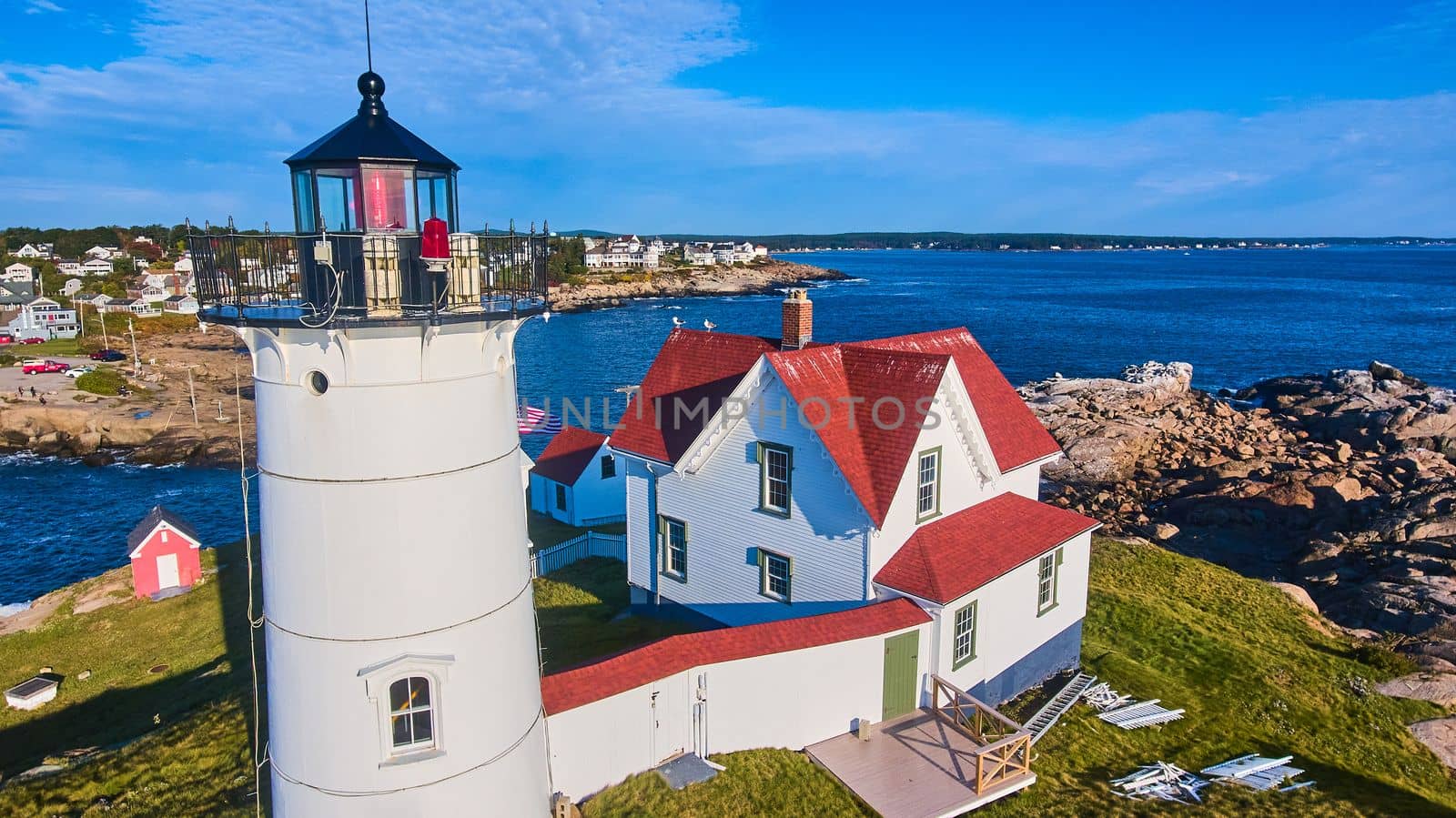 Up close aerial of lighthouse in Maine on island with town of homes in background by njproductions