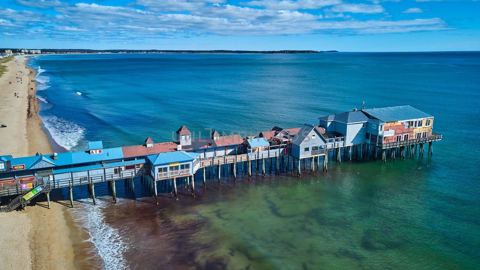 Beach on Maine ocean aerial over large wood pier covered in shops by njproductions