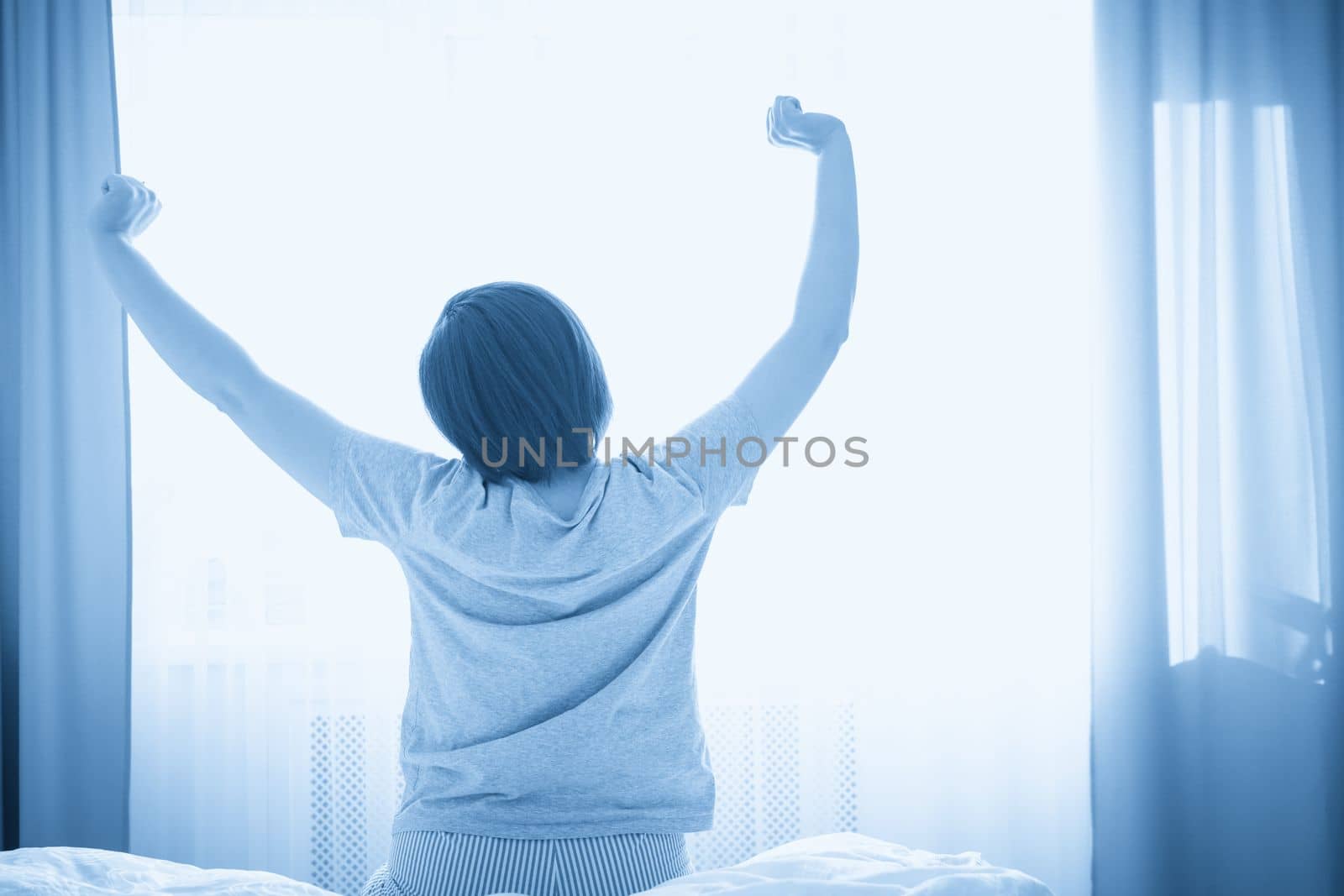 Woman stretching in bed in the morning by Mariakray