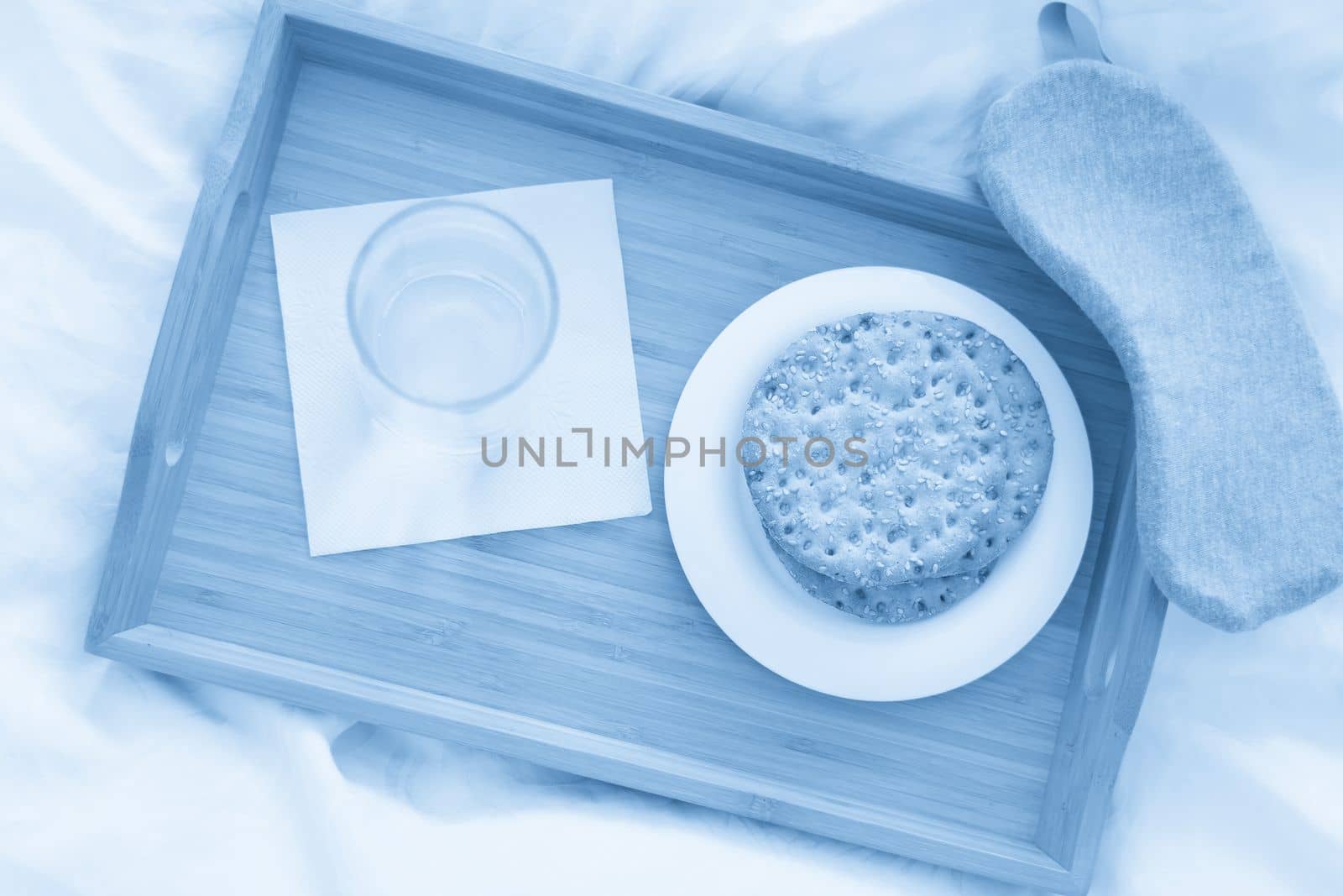 Tray with water and crackers breakfast on a bed