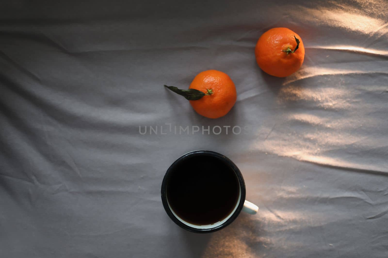 Winter cozy concept. Cup with coffee and tangerines on the bed. Copy space. Flat lay, top view.