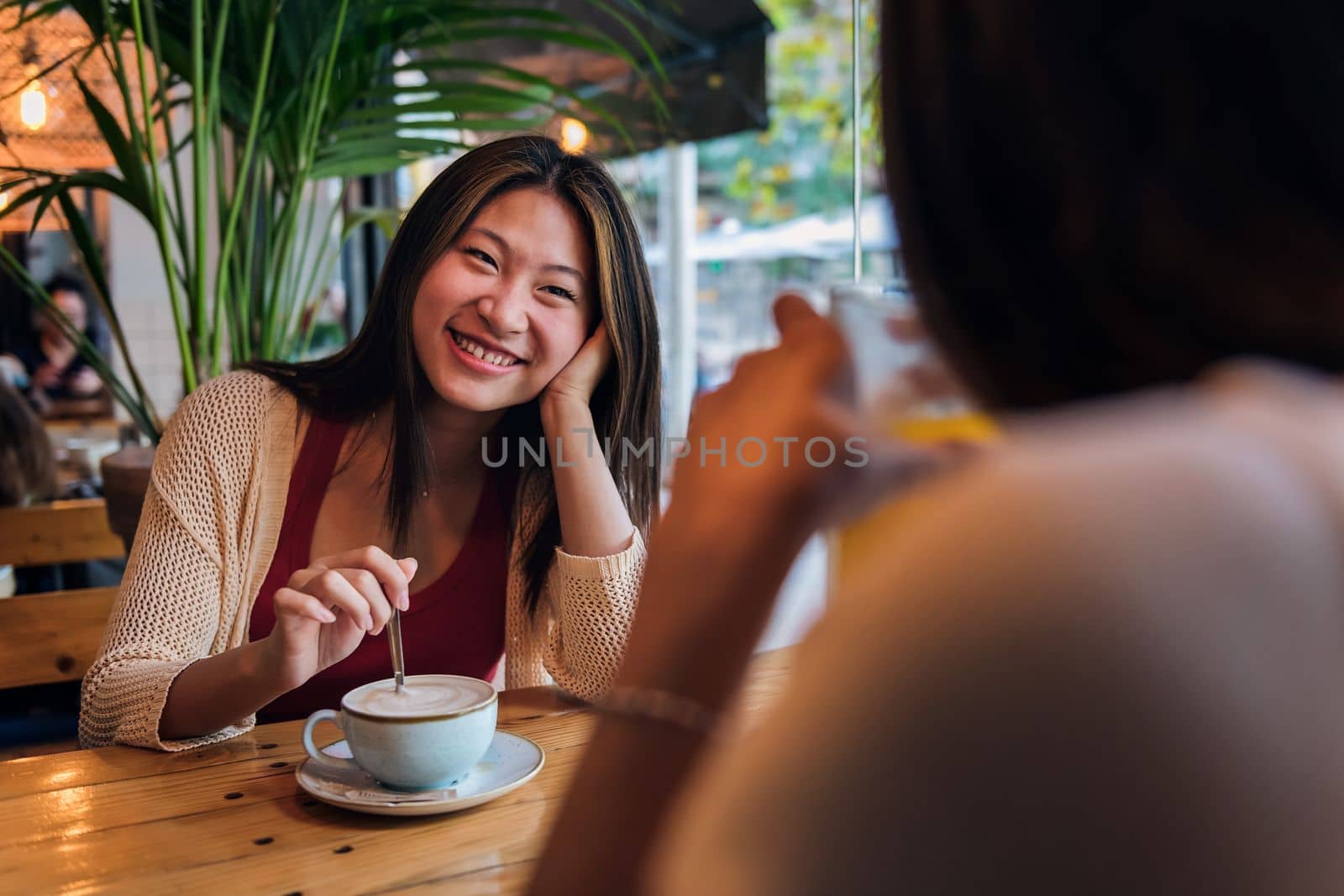 young asian woman smiling in love to her friend during their date in a coffee shop, concept of friendship and love between women