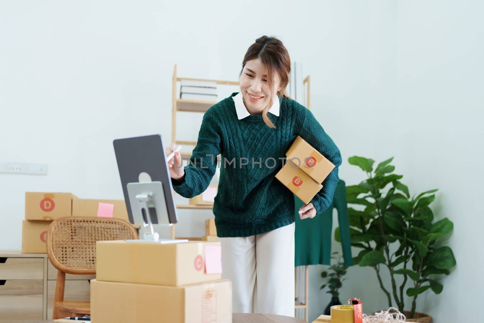 Starting small business entrepreneur of independent Asian female online seller packing products to send to customers and SME delivery concept.