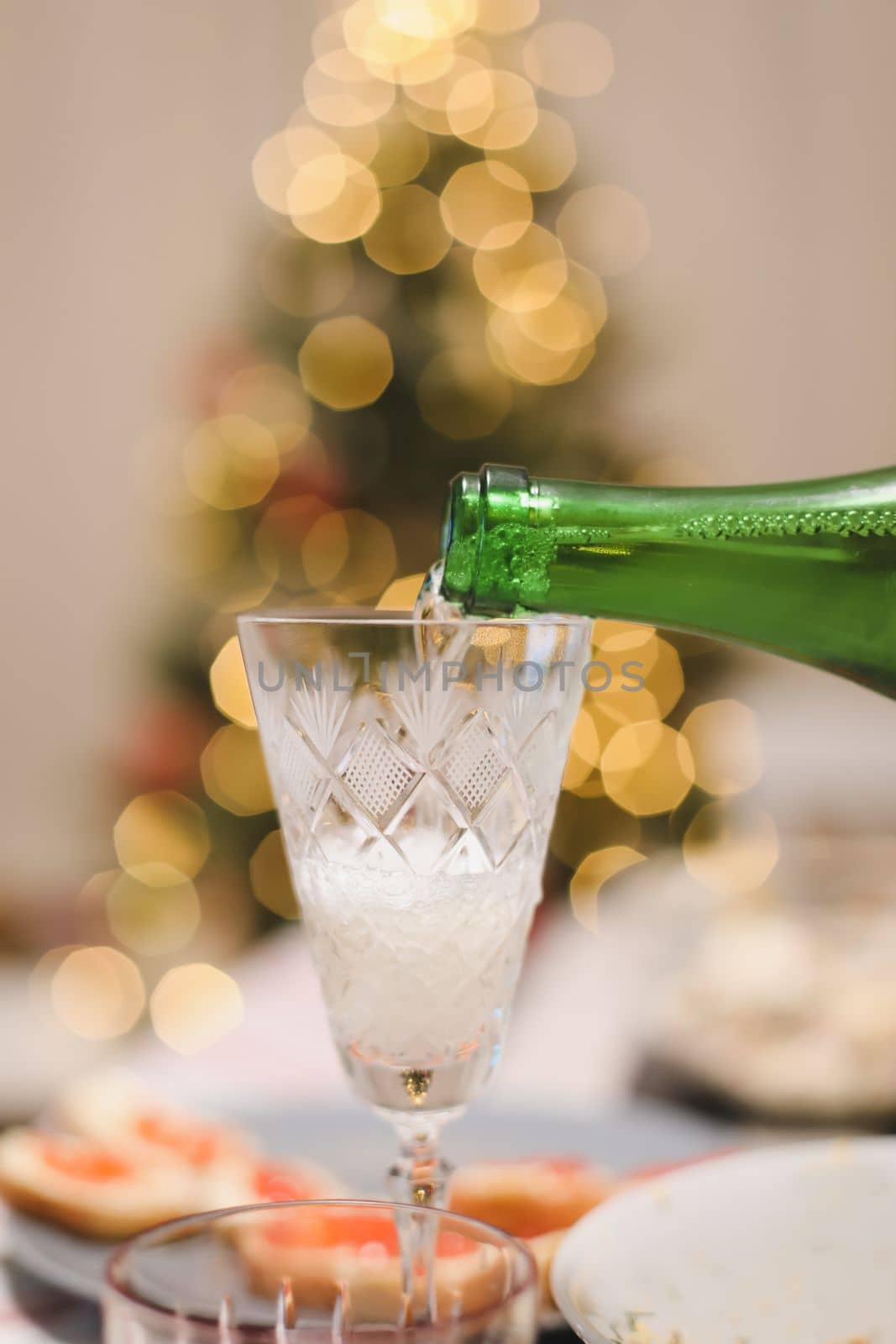 A glass of champagne on a table against Christmas tree.