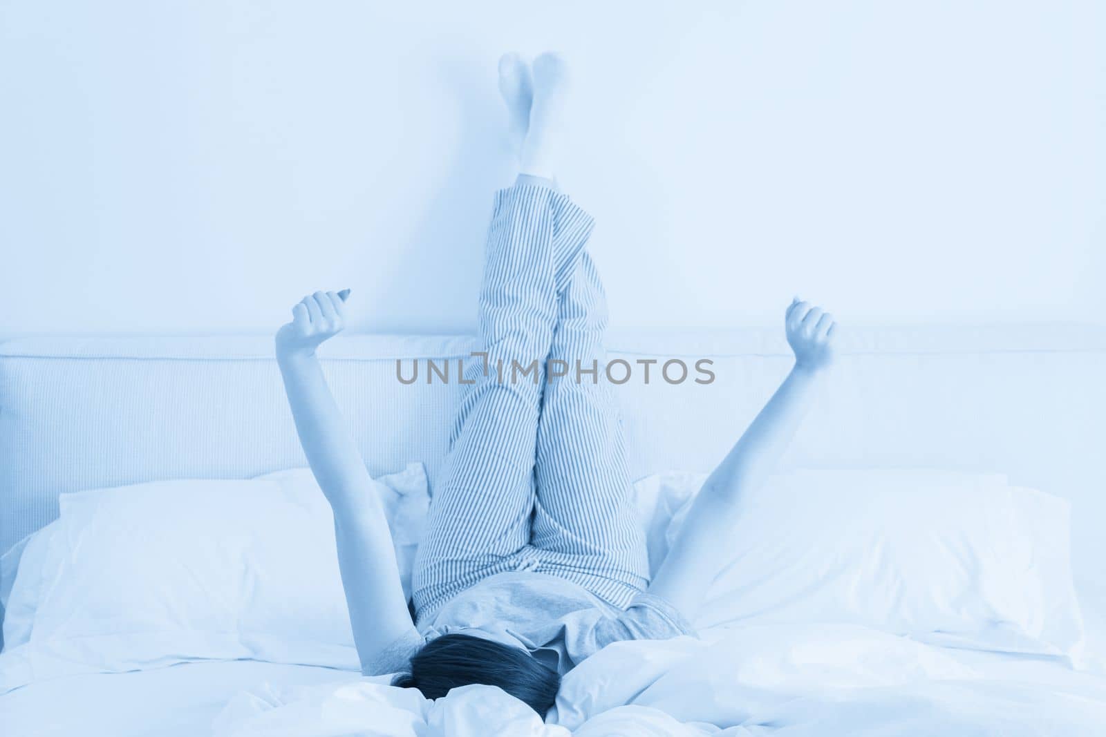 beautiful woman legs raised up high lying on bed in bedroom