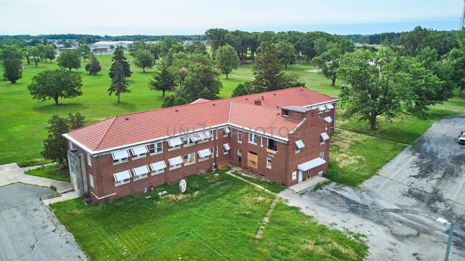 Old abandoned brick building aerial surrounded by trees by njproductions