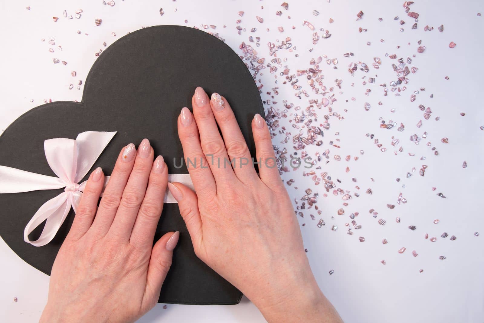 pink wedding manicure for the bride, a girls hand on the black heart shape box. High quality photo