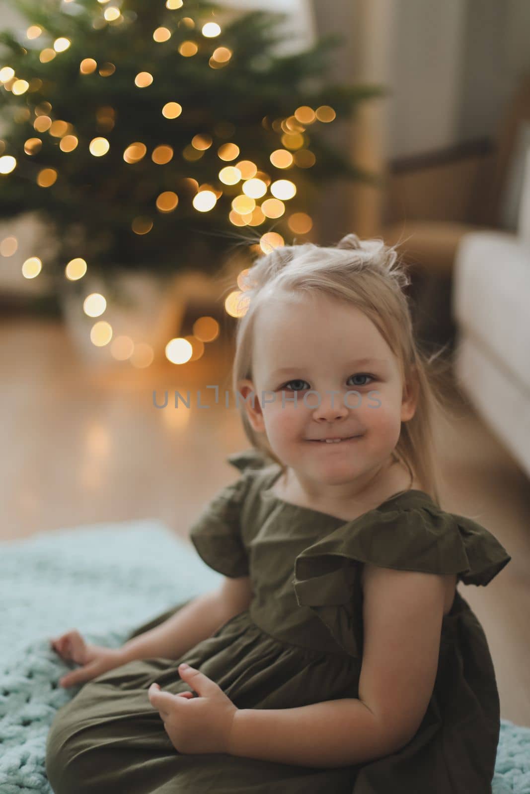 Cute little child girl and the Christmas tree indoors. Merry Christmas and Happy Holidays