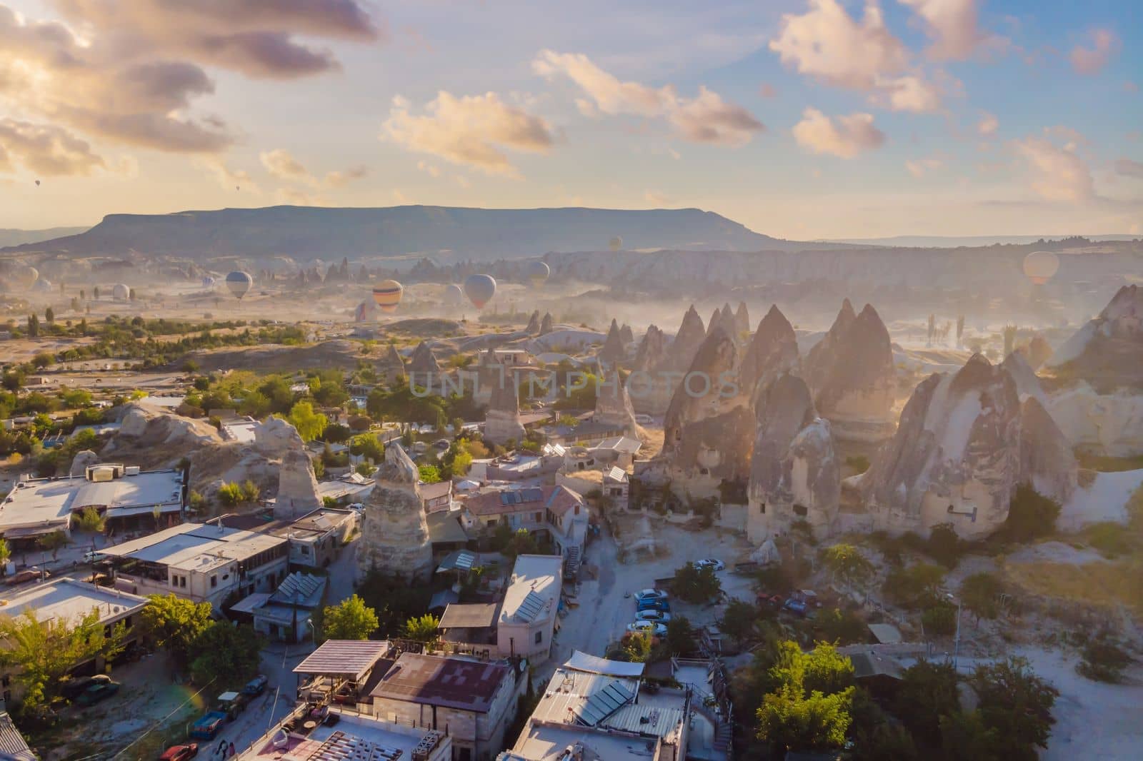 Colorful hot air balloons flying over at fairy chimneys valley in Nevsehir, Goreme, Cappadocia Turkey. Spectacular panoramic drone view of the underground city and ballooning tourism. High quality.